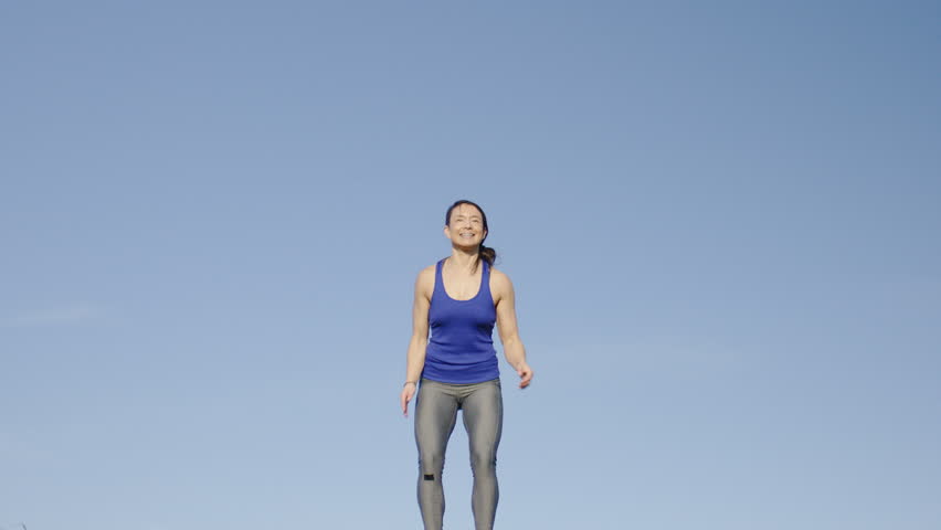 Young sporty female jumps up in happiness, in slow motion