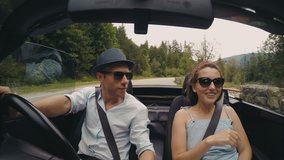 4K video: happy couple sings the songs while the roofless convertible car driving by the mountain road.