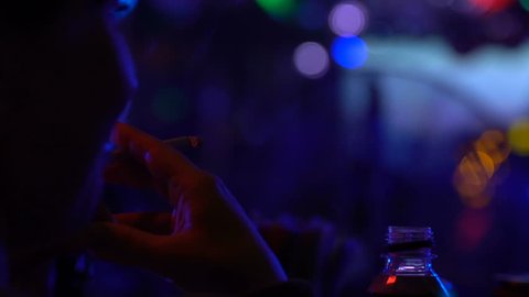 Smoking clubber relaxing cigarette in night club, party atmosphere, chill out