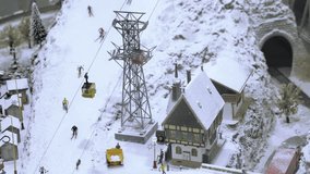 Mountain lift on ski slope with skiers. Miniature model railroad track. Transportation entertainment toy industry
