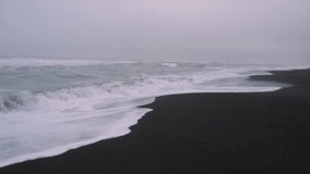 Slow motion footage of waves crashing at black sand beach Iceland during sunset