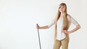 Cheerful attractive teen girl sings and dances with a broom like a microphone over white background.