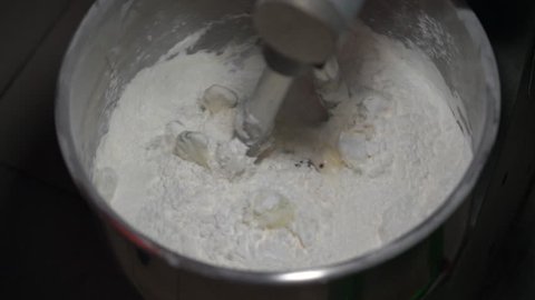 4K Slow Motion Movie of Flour, White Eggs and Water  in dough mixing machine, bakery ingredient mixed in the machine