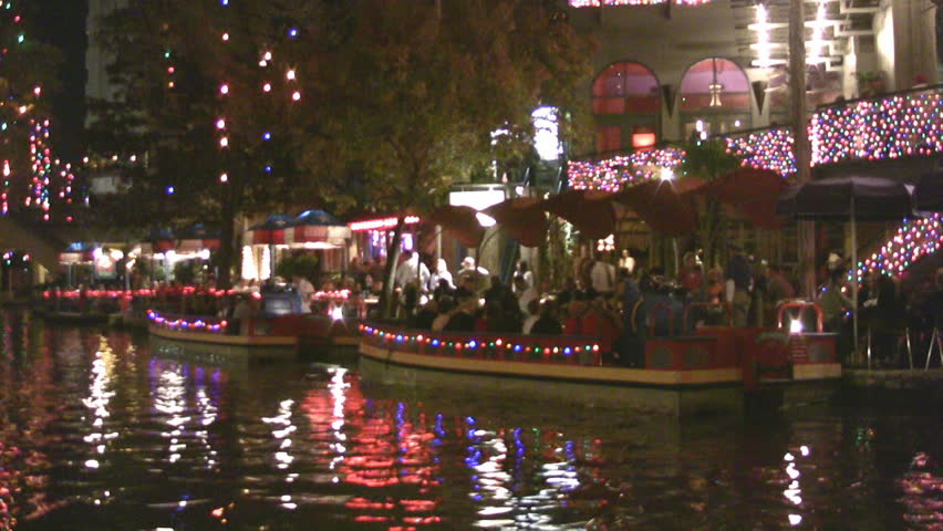 Video night Christmas lights of the San Antonio Texas Riverwalk. Tourists at restaurants and shops. Vacation area. Tourists eating at outside tables with bright lights and festive holiday atmosphere.