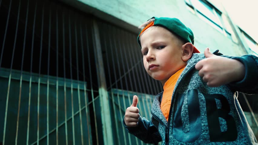 Boy shows class with thumbs up posing on camera standing in a backstreet