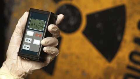 Radiation supervisor in glove with geiger counter checks the level of radiation in the radioactive zone