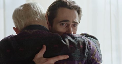 The last farewell to an adult son with an old father near the window. Strong emotional scene.