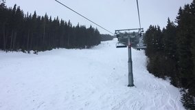 1080 HD time lapse hyper lapse video clip of four person ski chair lift climbing through forest trees on a misty mountain