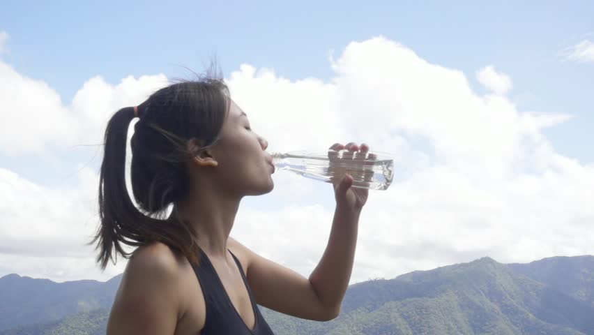 slowmotion shot woman drinking water after run