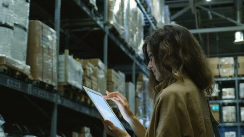 Beautiful woman with a tablet computer pc looking for a product in a storage room