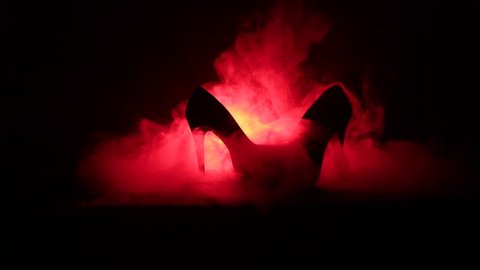 Black suede high heel women shoes on dark toned foggy background. Close up. Women power or women domination concept. Selective focus. Slider shot