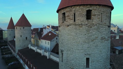 Close aerial of Tallinn old town wall's tower opening onto St Olaf's church during sunset