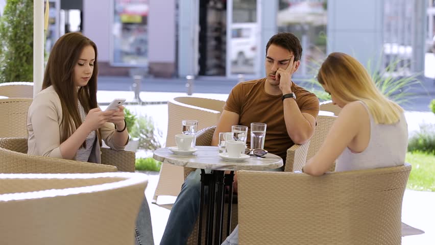 Bored young man sitting with friends who are spending time on their phone Royalty-Free Stock Footage #1010471093