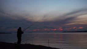 Fisher sits and catch fish against beautiful landscape. 4k video.