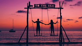 Silhouette loving couple in love on a picturesque wooden swing at colorful sunset on background. Authentic romantic couple on the beach. Honeymoon vacation and lifestyle concept. - Powered by Shutterstock - Get 15% off with code: PIKWIZARD15