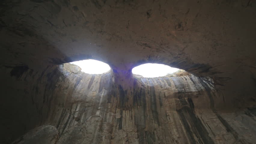 Prohodna cave also known as God's eyes near Karlukovo village, Bulgaria. Sun beams coming from the Gods eyes and lighting the cave. Royalty-Free Stock Footage #1010485067