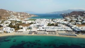 Aerial drone bird's eye view video of iconic pareadise organised beach of Ornos in island of Mykonos, Cyclades, Greece