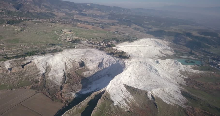 Rising aerial drone footage of calcium deposit travertines and wide overview of ancient Hierapolis ruins with Pamukkale, Denizli, Turkey. 4k at 23.97fps