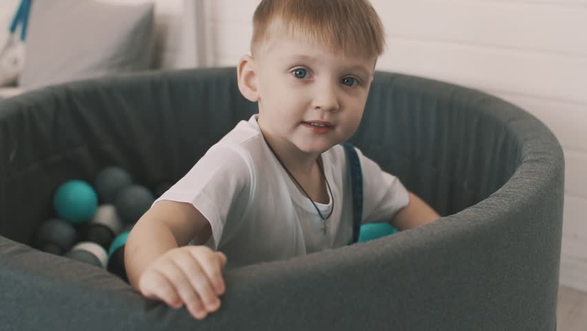 Little boy play in pool of coloured balls.