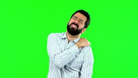 Handsome man suffering from pain in shoulder with beard on green screen chroma key