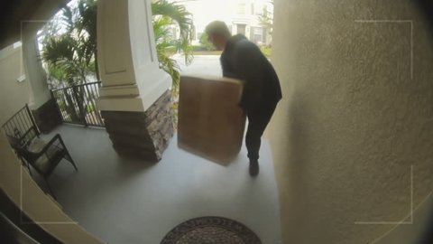 Person stealing delivery package from porch steps, surveillance camera view 