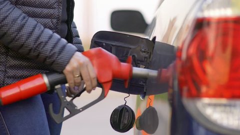 A woman runs a gasoline car at a gas station. Close-up.