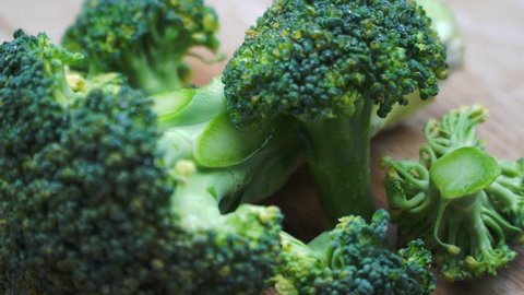 Fresh green broccoli and chopped broccoli are on the rotating wooden table. 4K