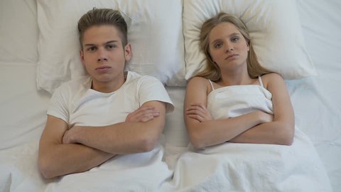Upset young couple lying in bed, sexual problems, relations misunderstanding