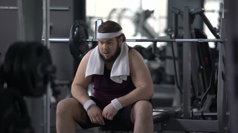 Funny overweight male pretending to be muscular and strong in gym, insecurities