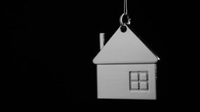 Metal key holder with house shape hanging and rotating over black background - Powered by Shutterstock - Get 15% off with code: PIKWIZARD15