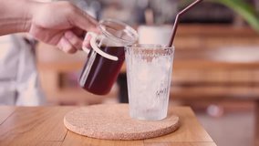 Pouring black coffee on one glass of ice with smooth motion