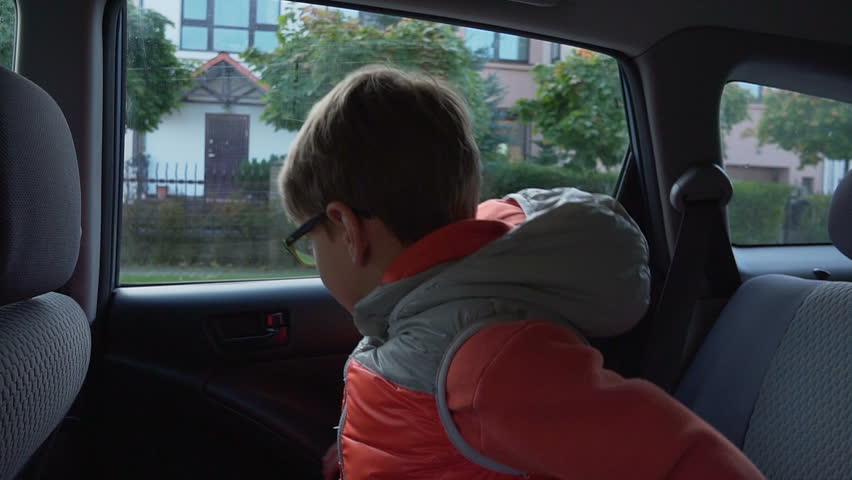Elementary-school student goes to school. The boy out of the car and waving to his parents Royalty-Free Stock Footage #1010527004