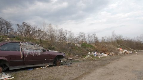 Panoramic view of illegal garbage dump with old abandoned rusted cars in city. Trash and construction waste polluting city area. Environmental problems and pollution concept.