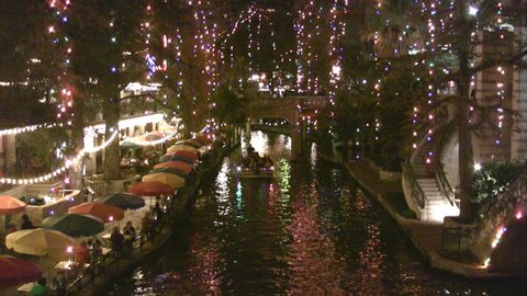 Video night Christmas lights of the San Antonio Texas Riverwalk. Tourists walking by restaurants and shops. Vacation area. Bright lights and festive holiday atmosphere. Foot bridge in distance. Stockvideó