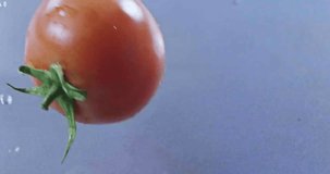An appetizing ripe tomato falls into the water. Slow motion 2k video shooted on 240 fps