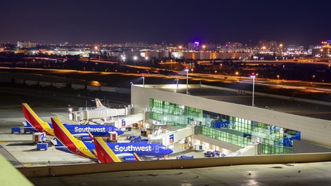 Ft. Lauderdale, FL - 2018: Southwest Airlines Night Timelapse at FLL Hollywood International Airport featuring Terminal 1 Concourse Building Exterior with Traffic Lights Moving in the Cityscape