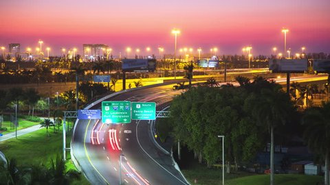 Ft. Lauderdale Florida Interstate Traffic Timelapse during Early Morning Dawn with Moving Lights from Cars Driving near FLL Hollywood International Airport in front of a Vibrant Colored Sky