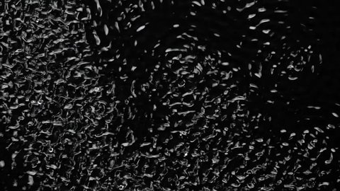 Vibrations and dark water liquid over a subwoofer audio speaker. Black background. Slow motion