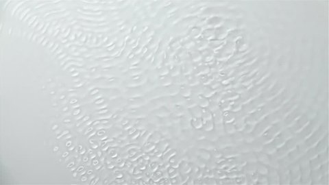 Reflection of the water creating waves caused by sound vibrations. White background. Slow motion