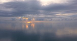 Drone fly over the calm sea with pastel sunset skies. High altitude over the water into the the horizon line