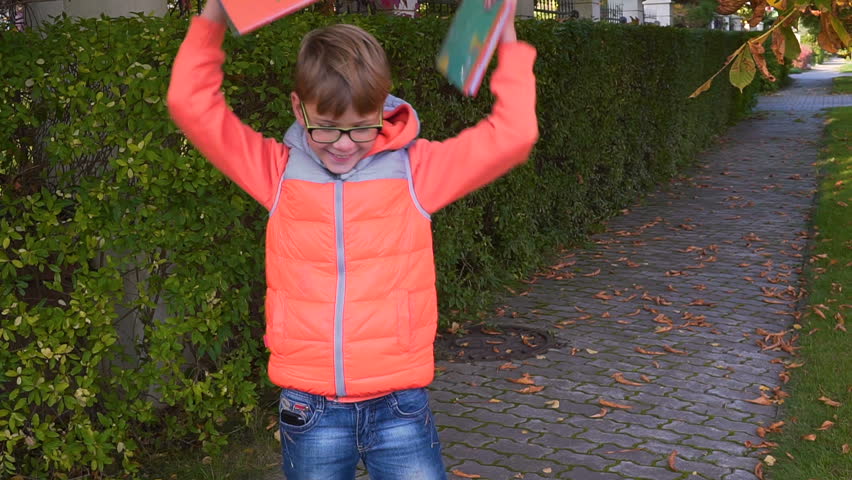 portrait of a happy schoolboy who waving textbooks and smiling. The end of summer, the beginning of autumn