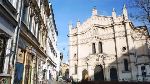 KRAKOW / POLAND - JANUARY 9, 2018: People near Tempel Synagogue in Kazimierz district, Krakow. Sunny winter day. Pan, tracking shot.