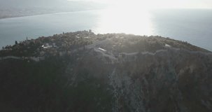 High altitude aerial drone video high key clifftop Alanya Castle panning left to reveal city center, beach at morning in Turkey. 4k at 23.97fps