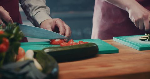 Slowmotion dolly shot, Chef cutting a tomato vegetable on a green cutting board with a lot of haze in the kitchen ending with a flare