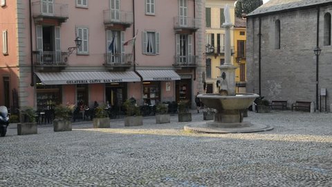 Real time of people relaxing at a terrace in front of a restaurant in an Italian square with a fountain