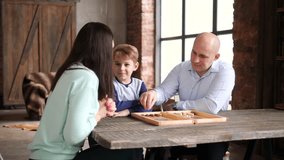 Mother, father, and son are playing checkers in the living room; Mom rolls the dice and makes a move - Powered by Shutterstock - Get 15% off with code: PIKWIZARD15