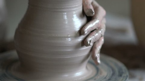 The potter works on a potter's wheel. Concept: handmade, workshop, pottery
