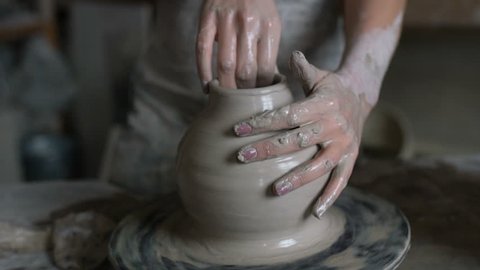 The potter works on a potter's wheel. Concept: handmade, workshop, pottery. Slow motion