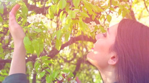 Beauty spring young woman enjoying nature in spring apple orchard, Happy Beautiful girl in Garden with blooming trees. Smiling Model girl smelling blossom flowers 4K UHD video 3840X2160