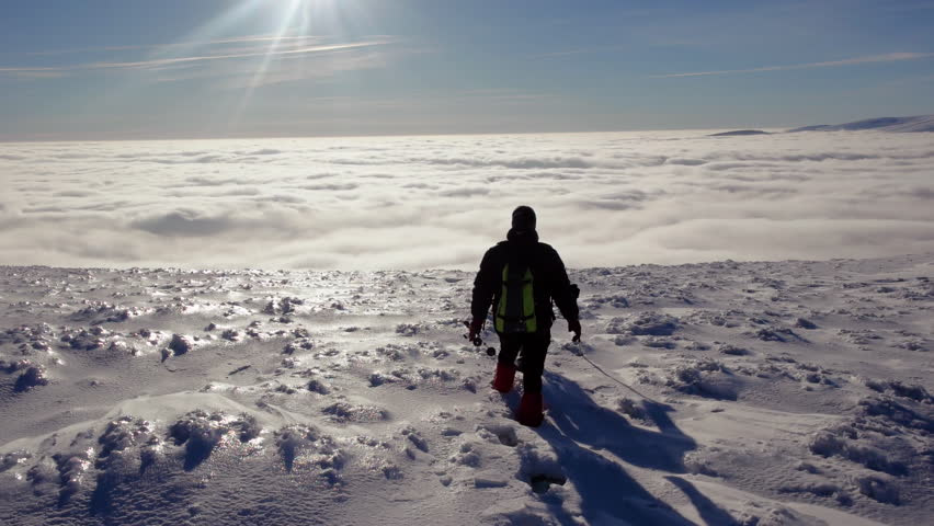 Travellers With Backpacks Make a Winter Hike Above the Clouds With a View of the Distant Peaks by a Coast of the Cloud Sea